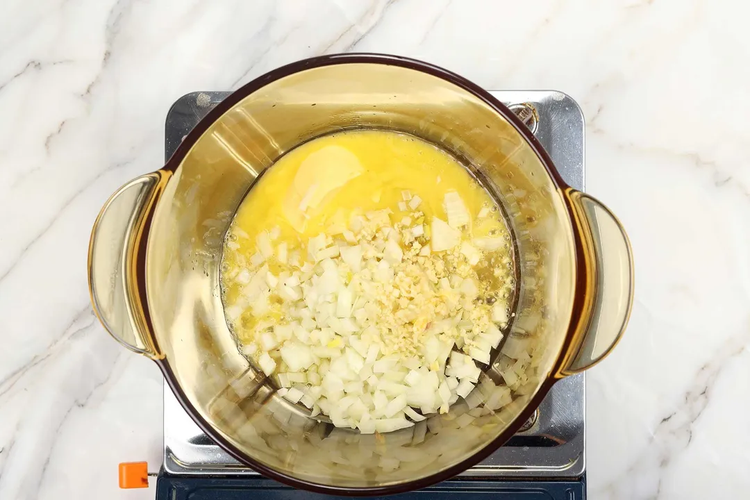 diced onion, minced garlic and butter cooking in a glass pot