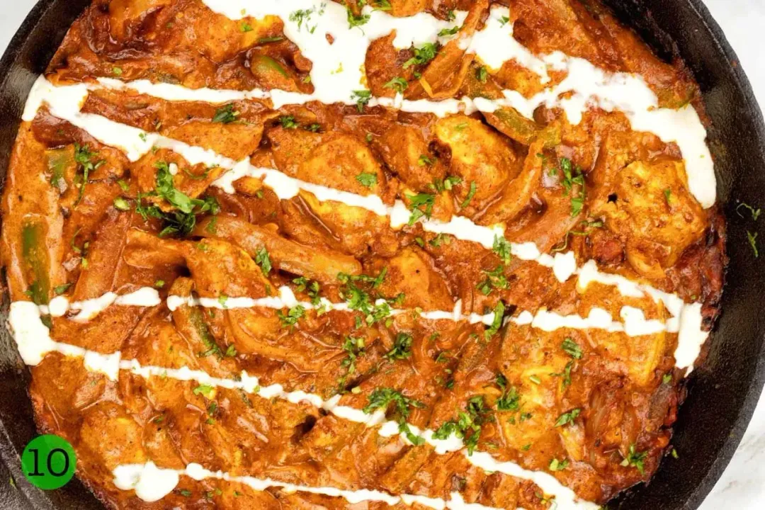 A pan of Chicken Tikka Masala garnished with drizzles of cream