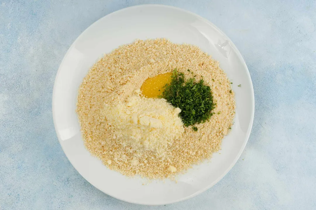 plain panko breadcrumbs, chopped parsley, parmesan and eggs on a plate