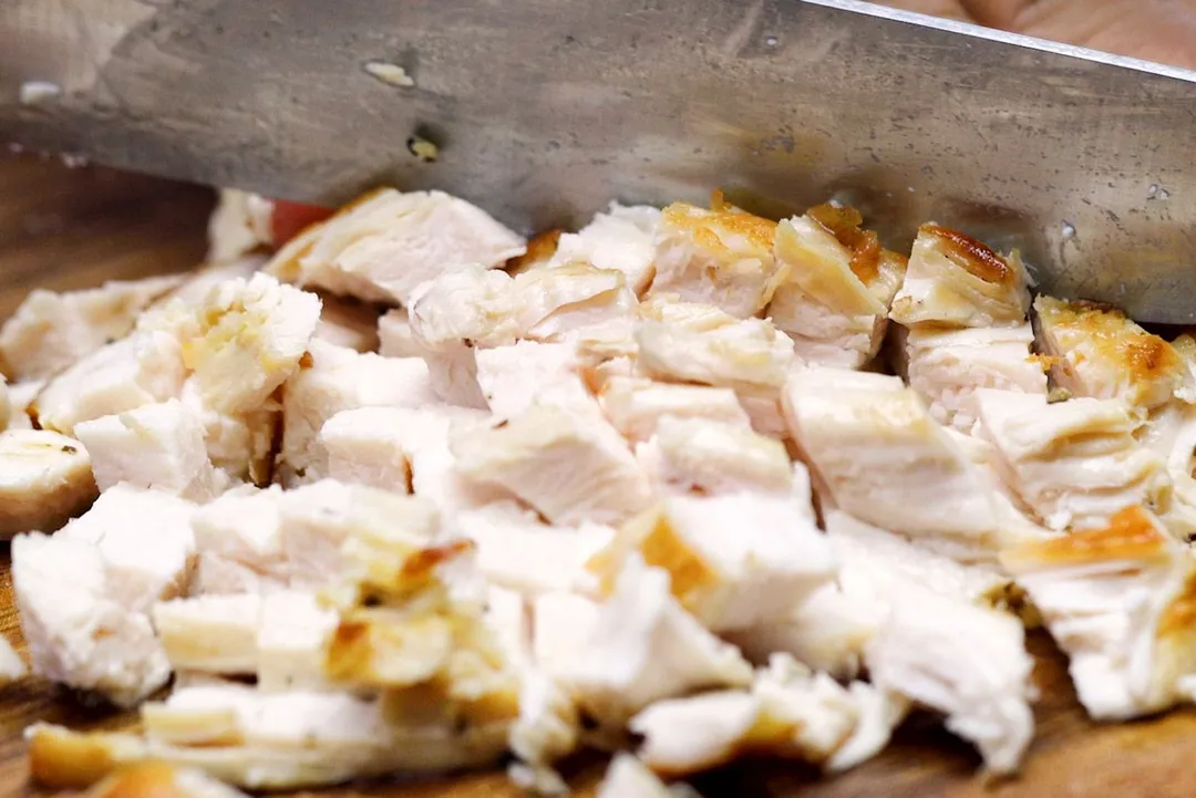 knife cutting chicken breast to cubes