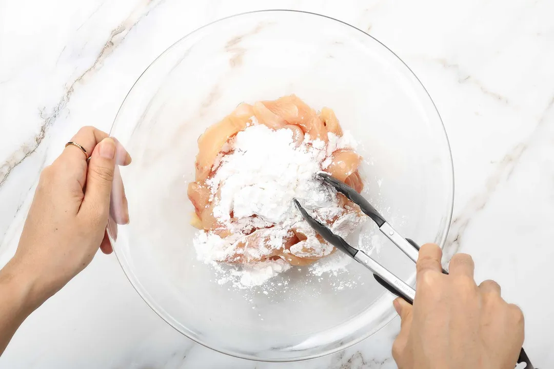 coating chicken slices with flour in a glass bowl