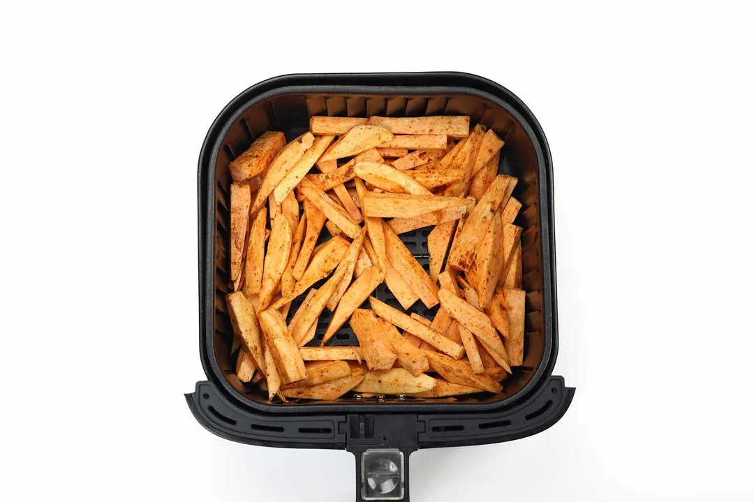 An air fryer basket containing sweet potato fries