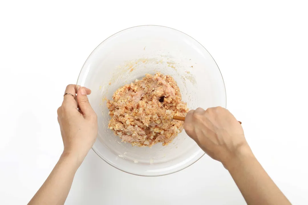Two hands mixing a bowl of ground meat