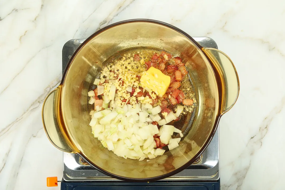 chopped onion butter garlic and bacon cooking in a pot