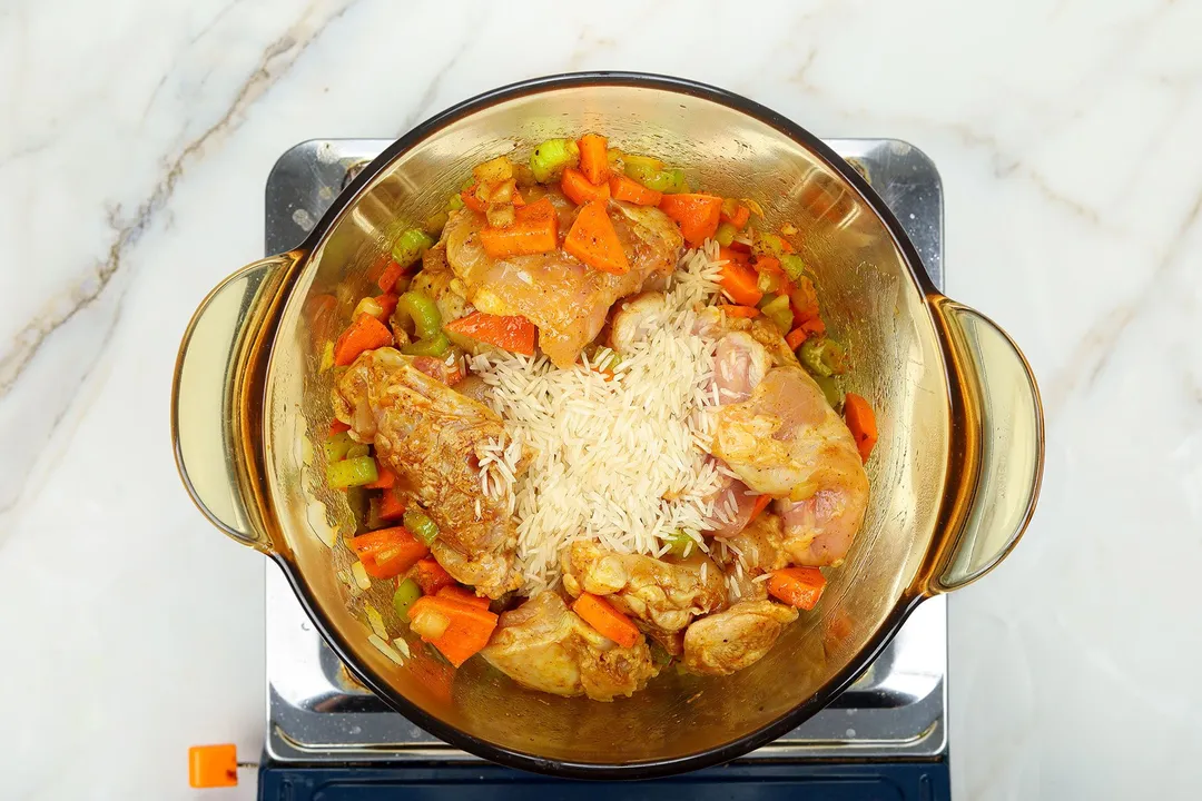 chicken thighs, rice and carrot celery cooking in a pot