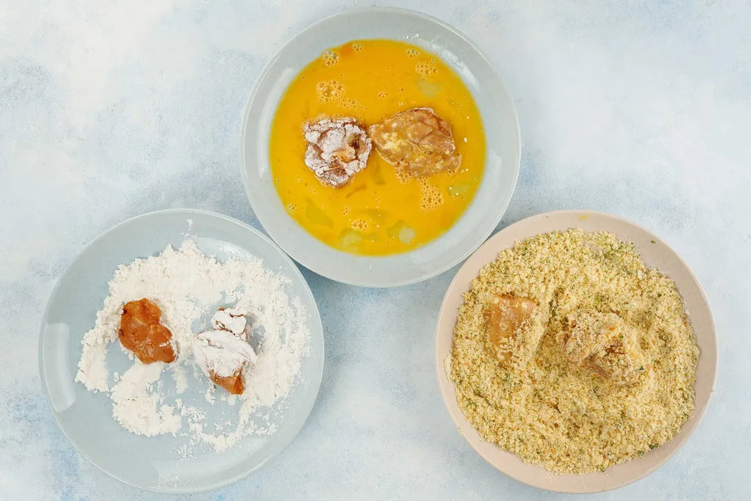 chicken nuggets on three plate: flour, eggs and breadcrumbs