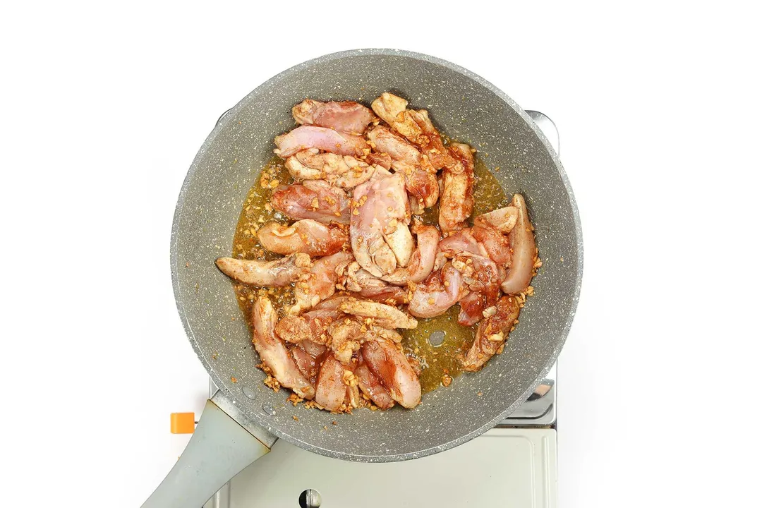 Chicken thighs being sautéed in a pan