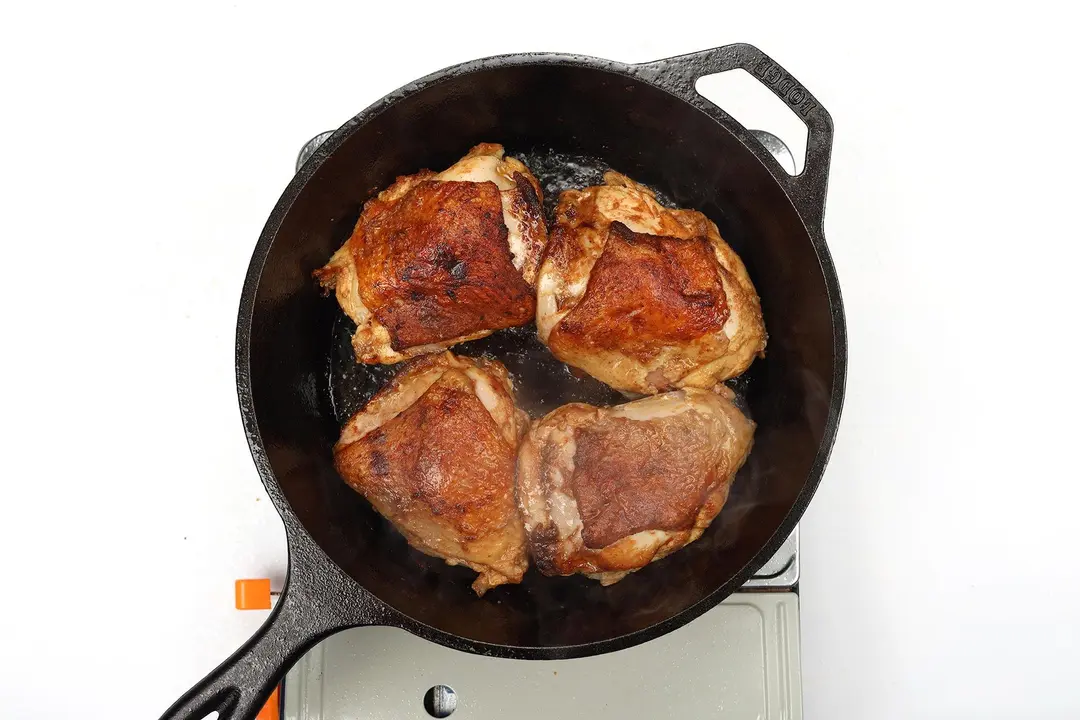 Four pieces of chicken thighs in a cast iron skillet