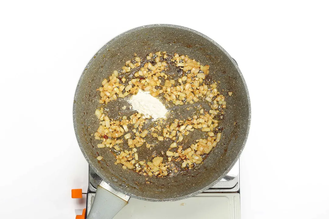 Minced garlic, diced onion, and flour being stir to cooked in a non-stick pan