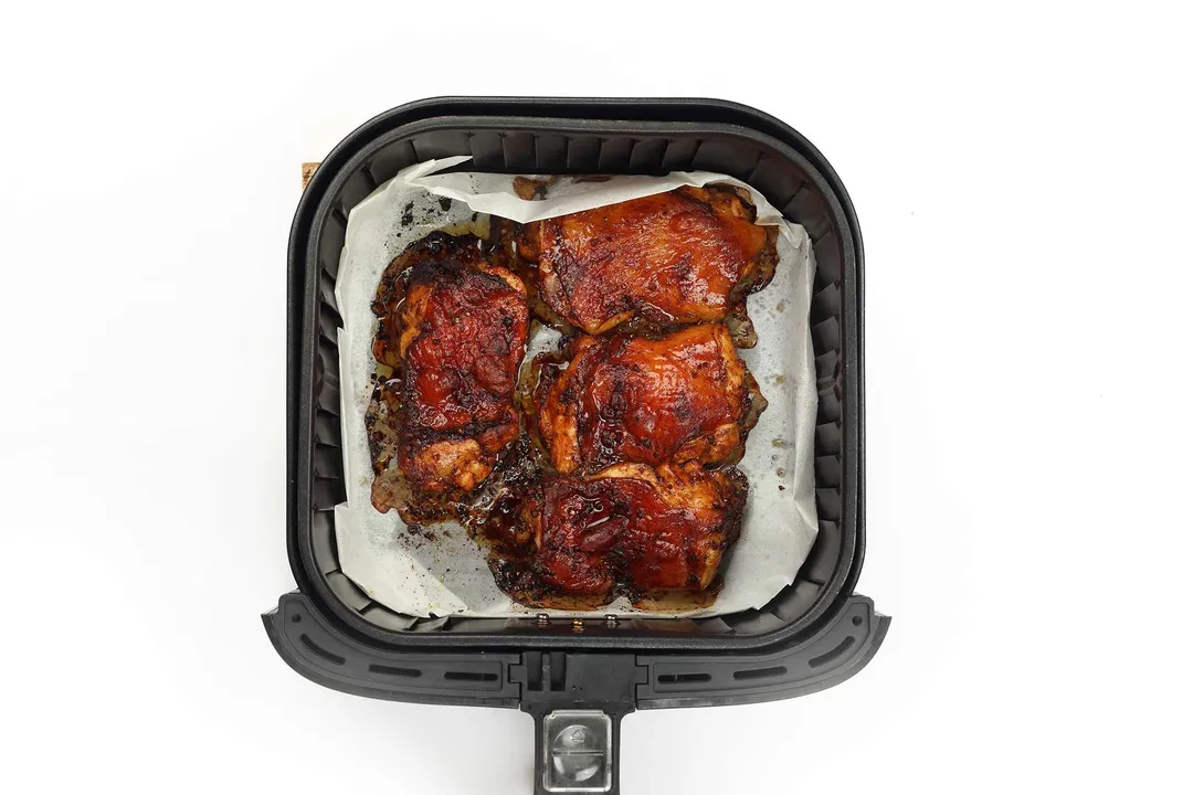 Four pieces of chicken thighs in an air-fryer basket