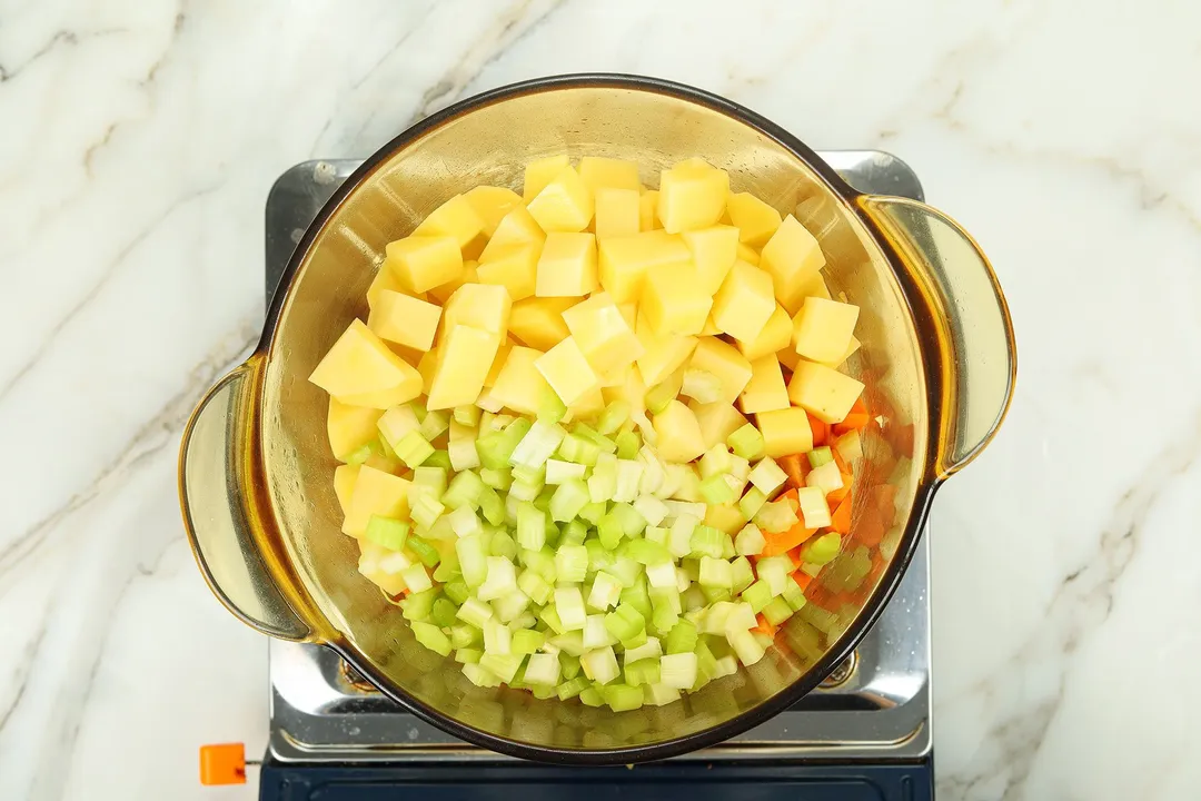 potato cubes, celery and carrot in a pot on a stove