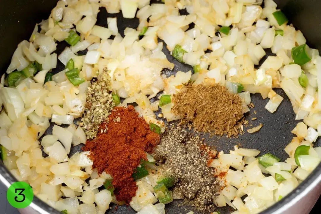 A pot cooking diced onion with some spices in the middle