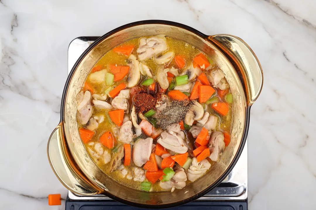 slices carrot celery mushroom and chicken cooking in a pot