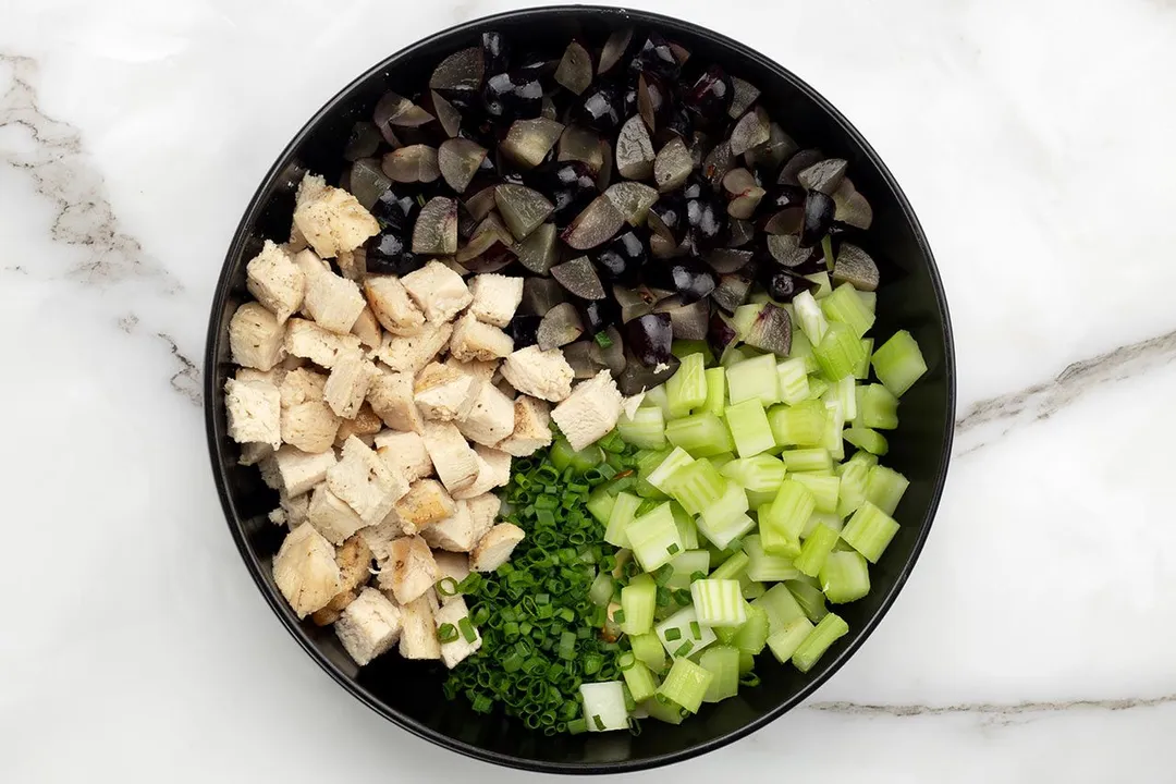 chicken cubed, celery cubed, grape cubed and chopped scallion in a black plate