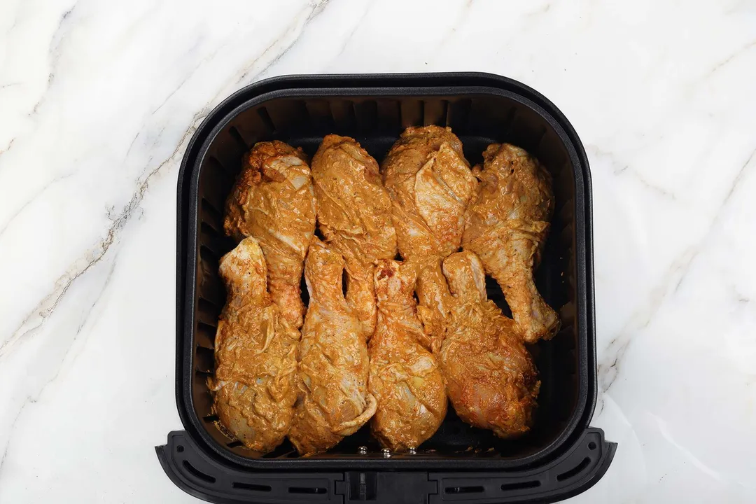 top view of marinated chicken drumsticks in a air fryer basket