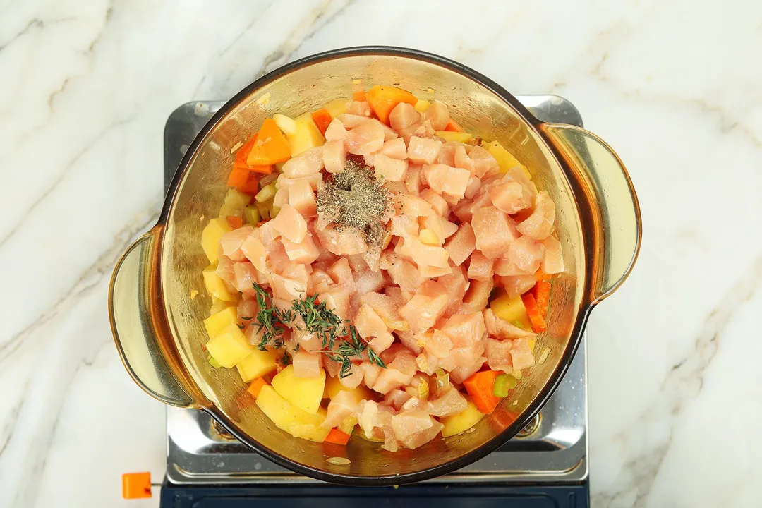 cooking chicken potato cubes, carrot, thyme, pepper in a pot