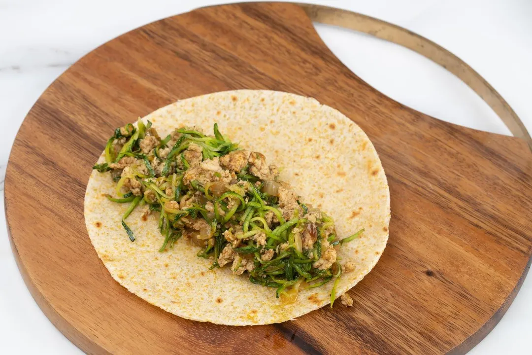 a tortilla with filling on a cutting board