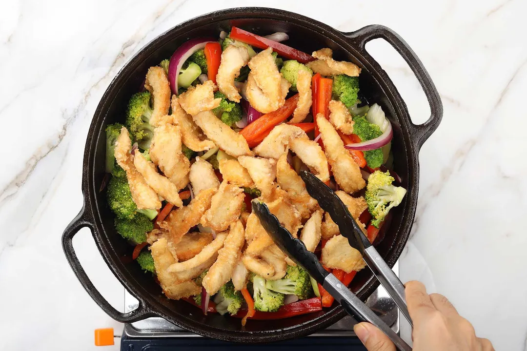 cooked chicken, broccoli florets, slices red bell pepper cooking in a cast iron skillet