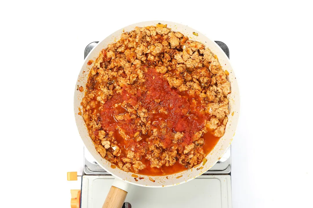 cooking tomato sauce with ground chicken in a skillet