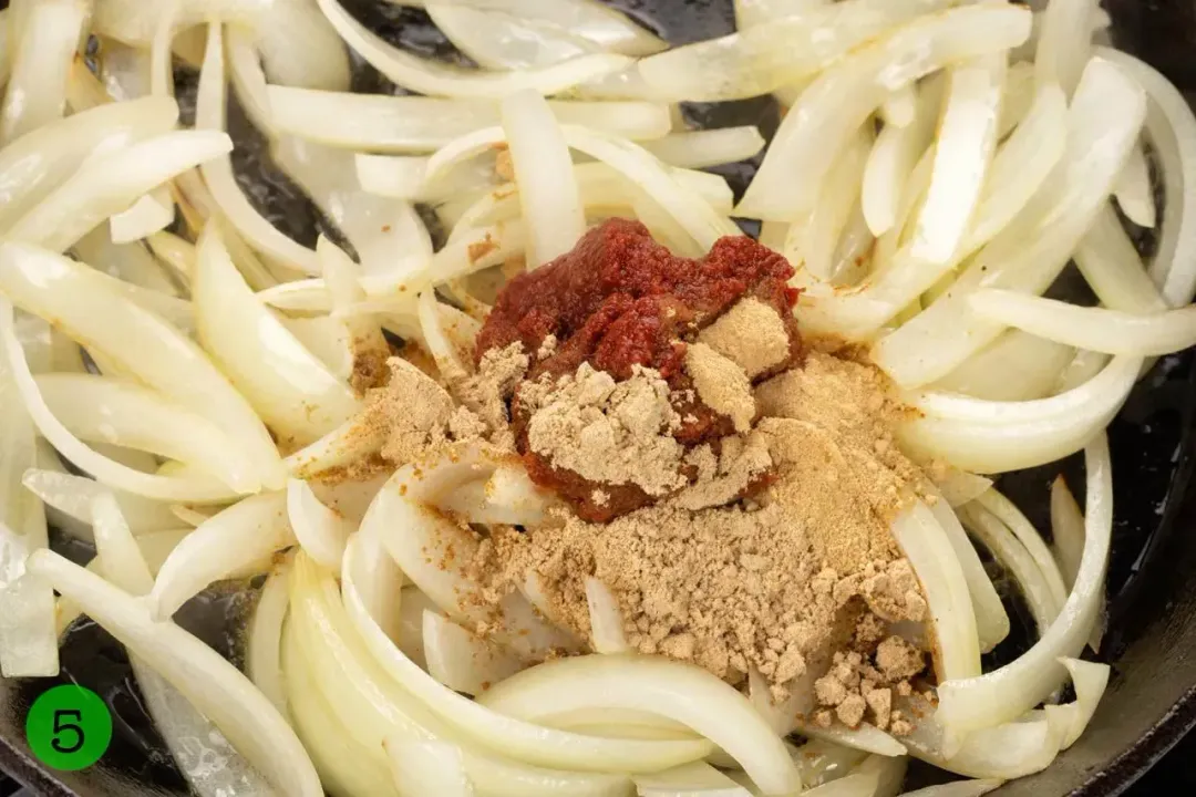 A pan cooking onion slices with spices in the center