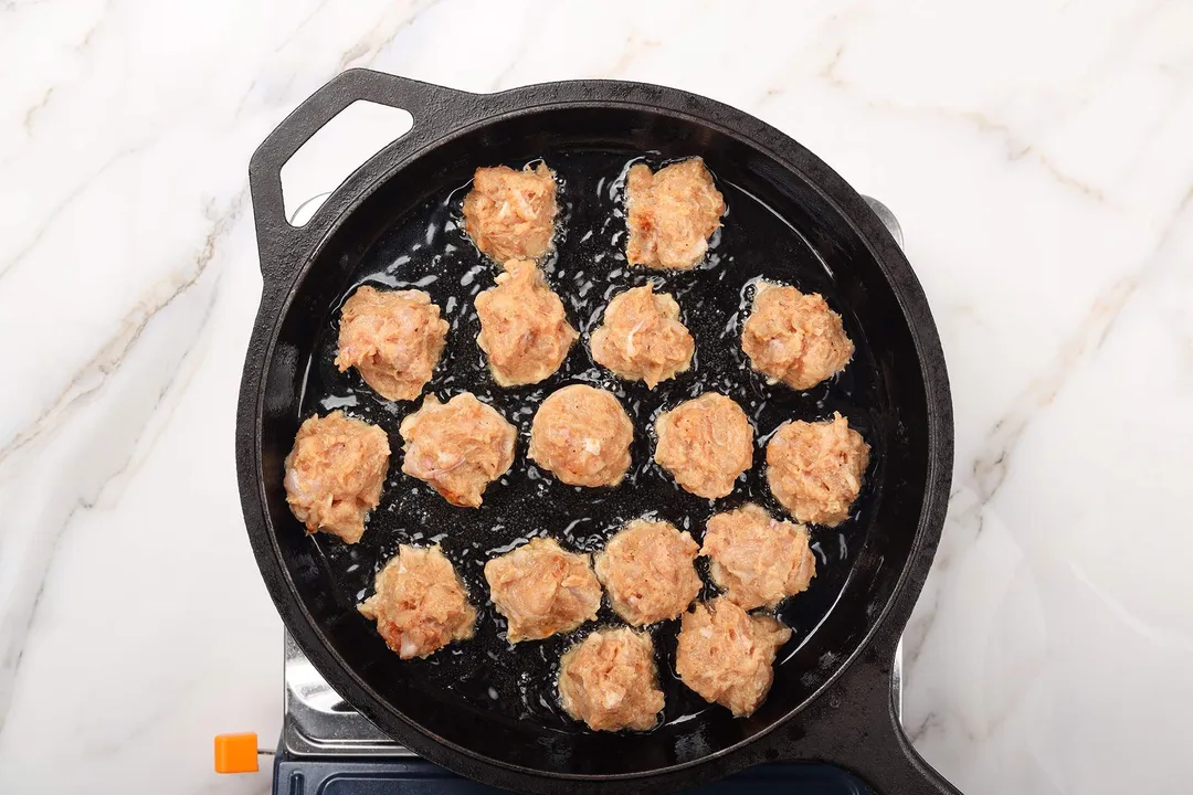 frying chicken scoops in a cast iron skillet