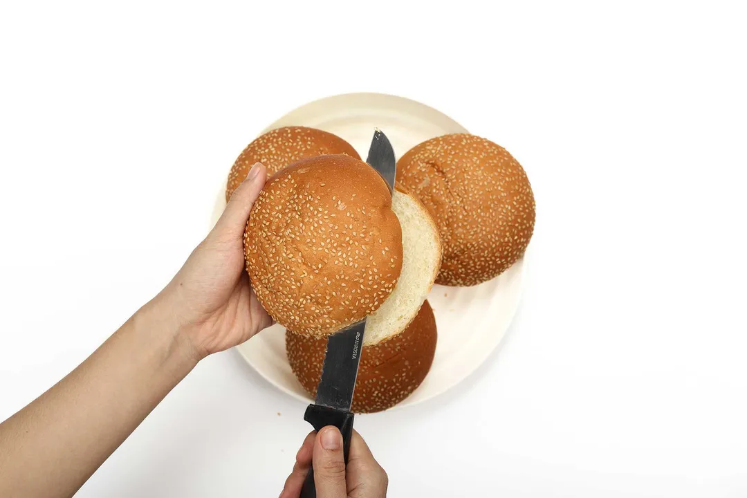 Hamburger buns being cut in half crosswise