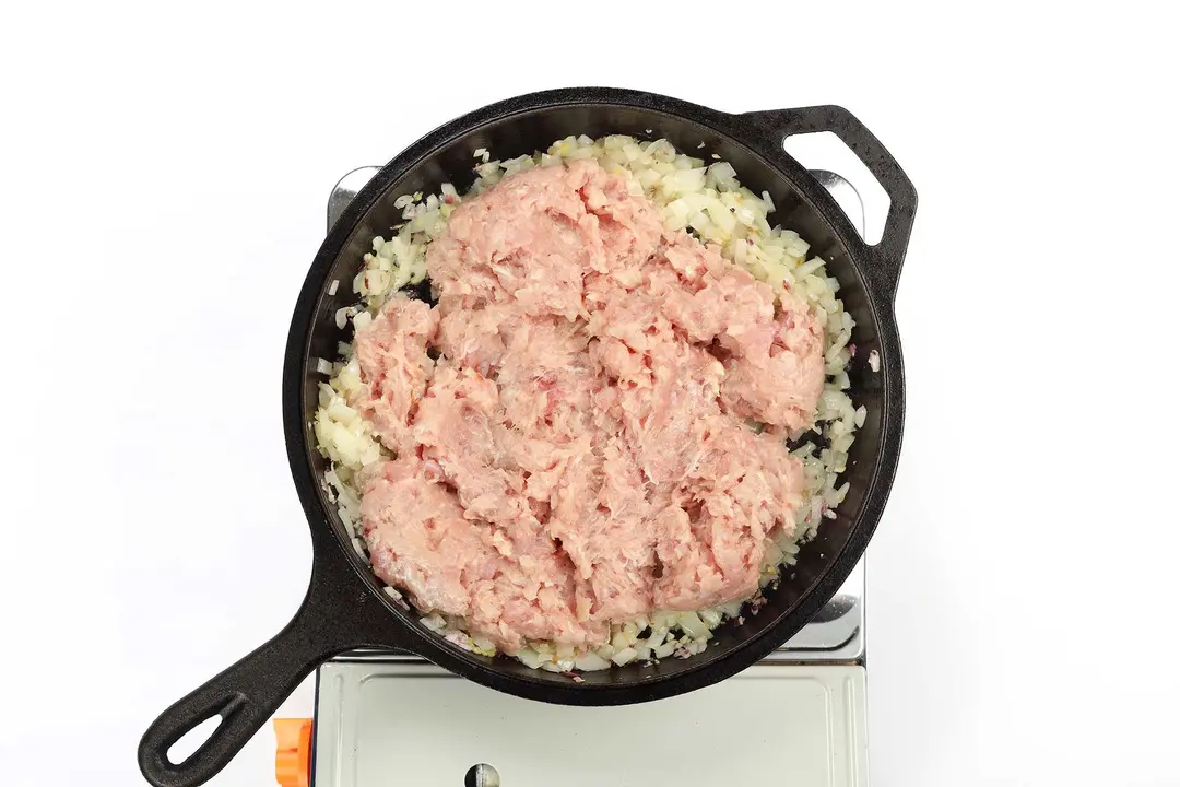 A skillet containing raw ground meat and diced onions