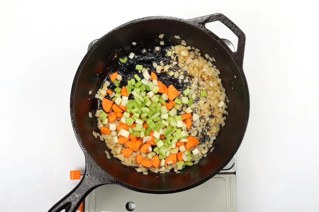 Sautéed diced carrots, celery, and onion in a cast iron skillet