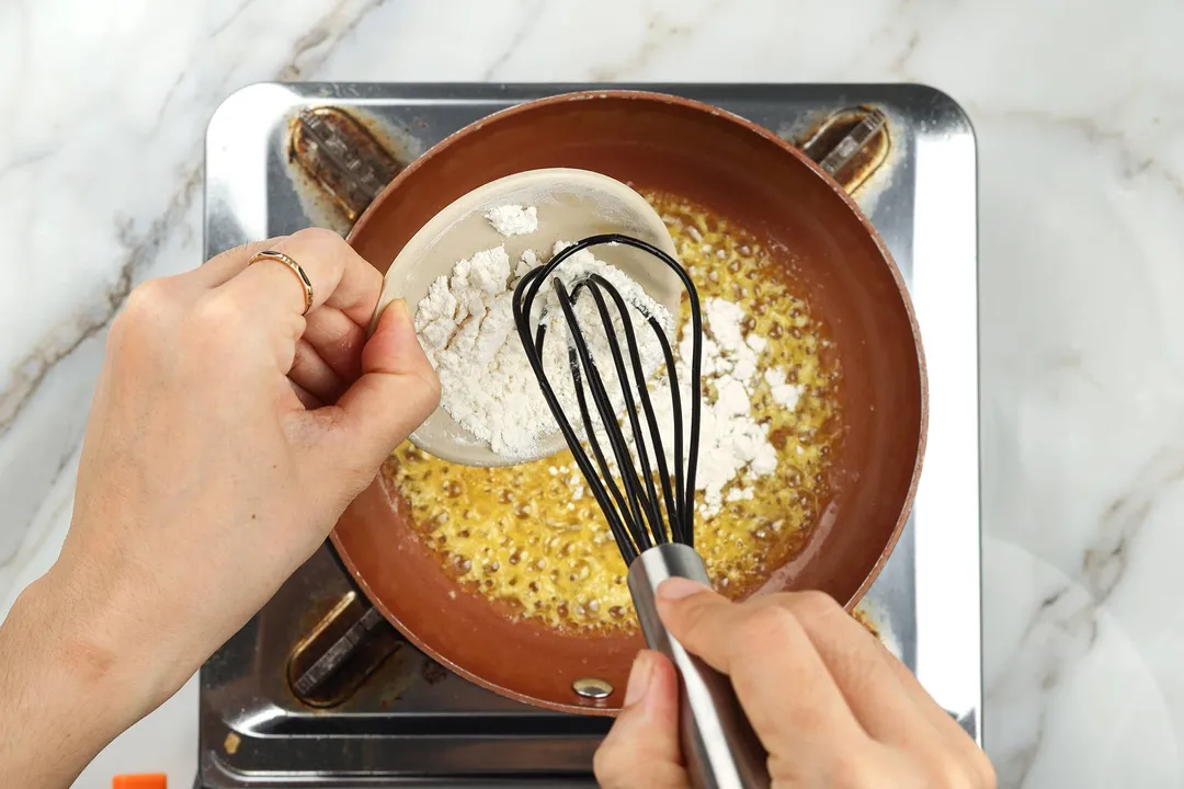 pouring flour from a small bowl into a skillet