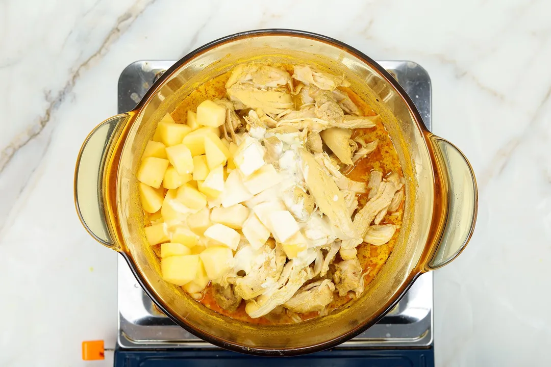 apple cubed, shredded chicken and heavy cream cooking in a pot