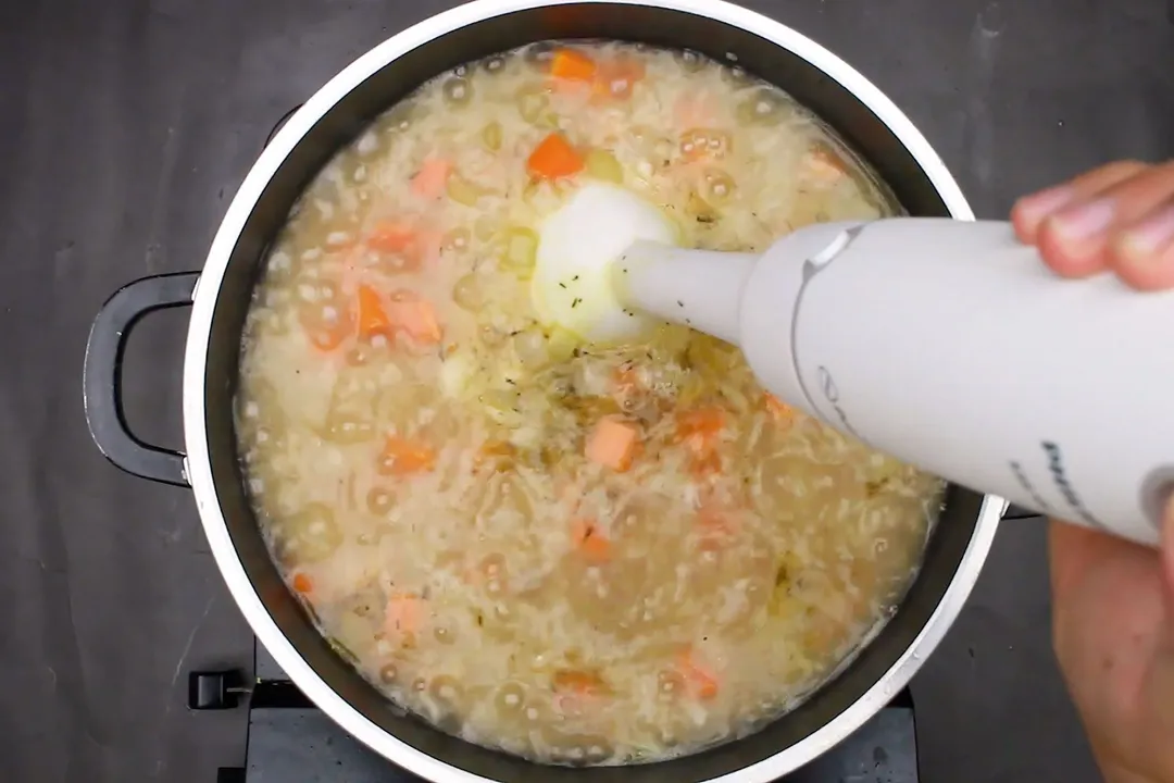 a pot of soup blending by an immersion blender
