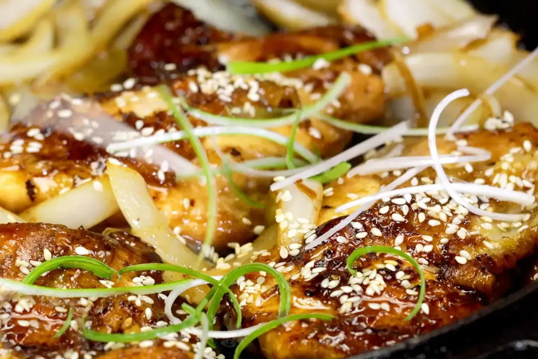 Grilled teriyaki chicken with white sesame seeds and shaved green onion put over the top