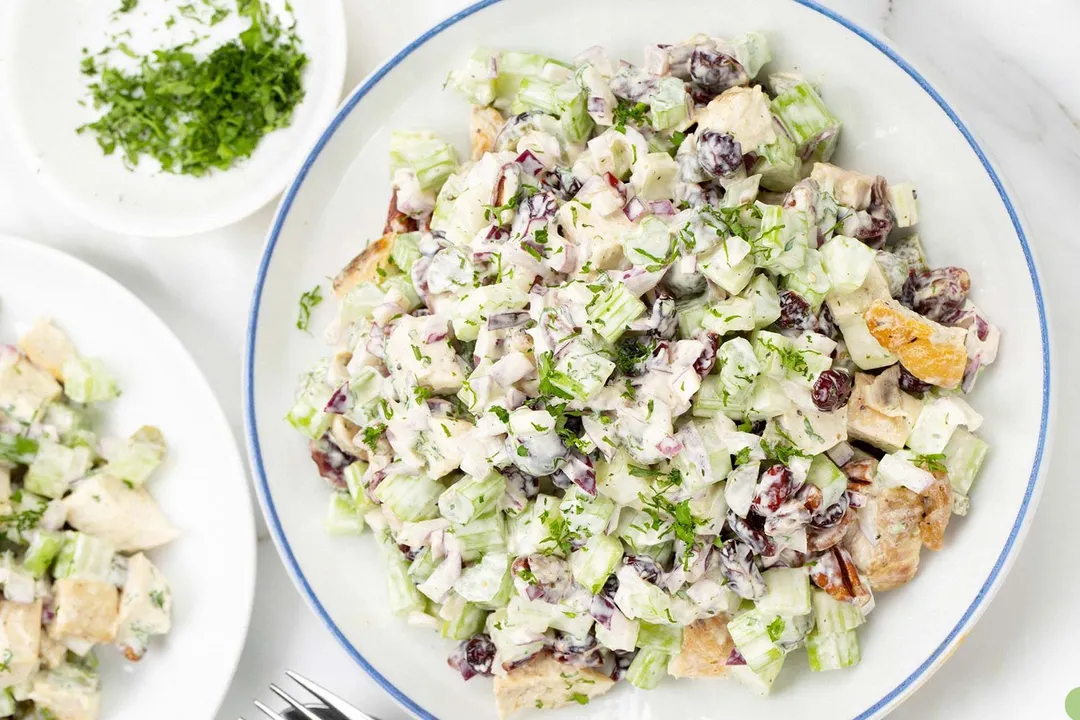 two plate of chicken salad and a small plate of chopped parsley