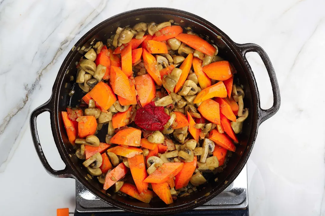 chopped carrots, tomato paste in a cast iron skillet