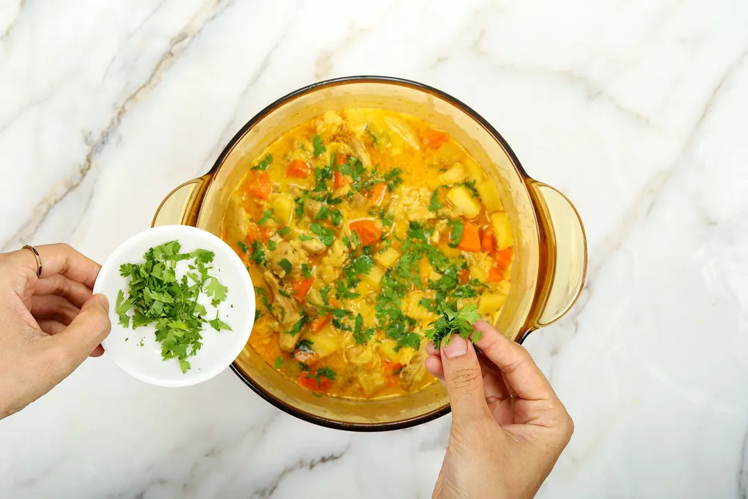 sprinkle chopped parsley from a small bowl into a pot of soup