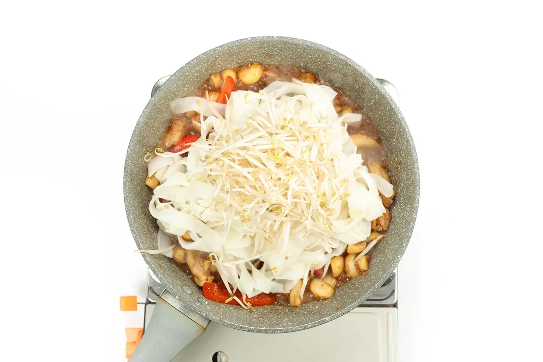 Rice noodles and bean sprouts in a pan with other ingredients