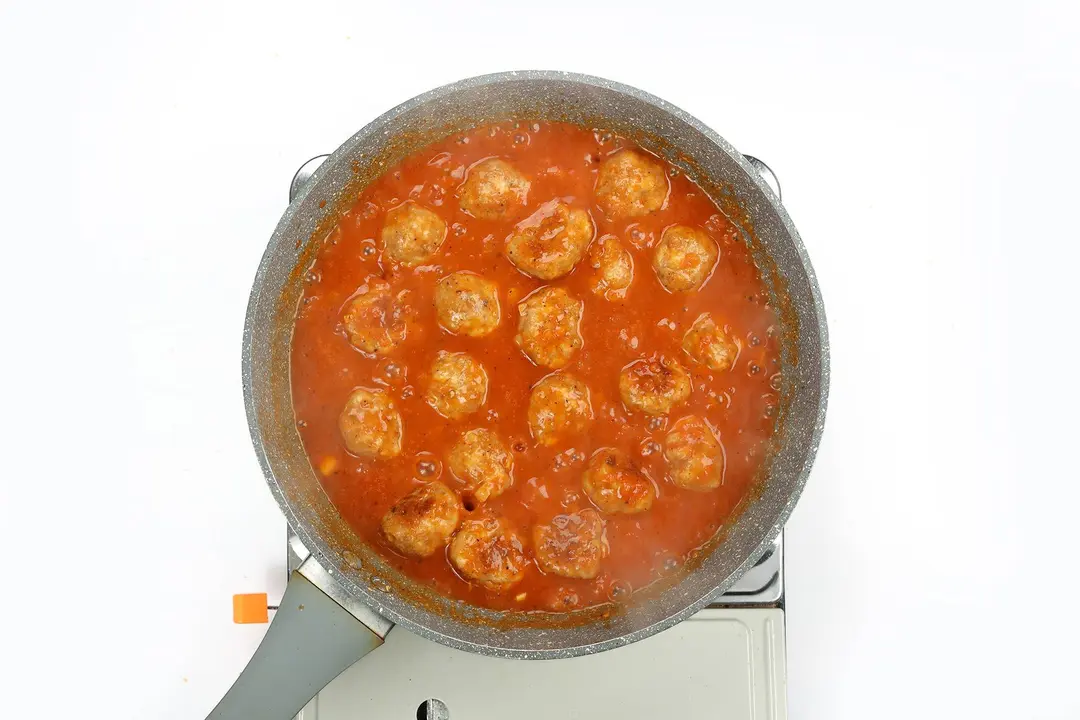 Chicken meatballs being cooked in tomato sauce