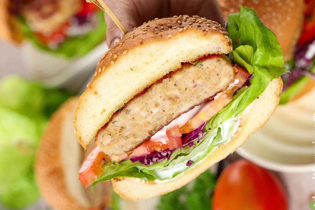 The close-up on a hamburger sliced in half held by a hand