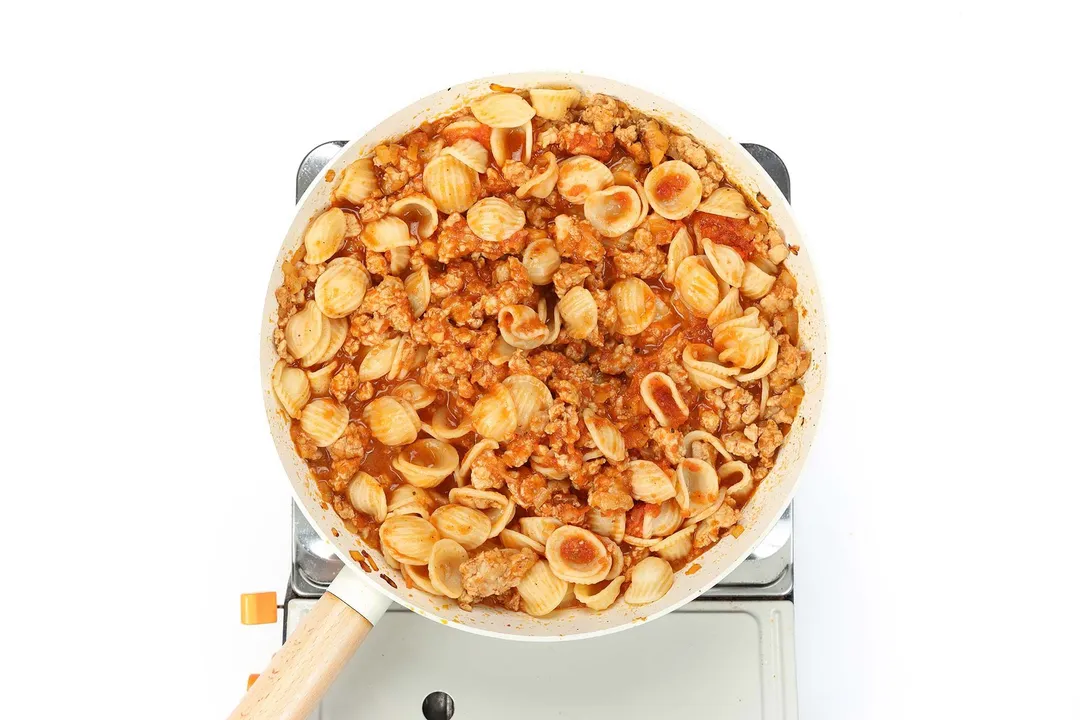 a skillet of cooked pasta and ground chicken