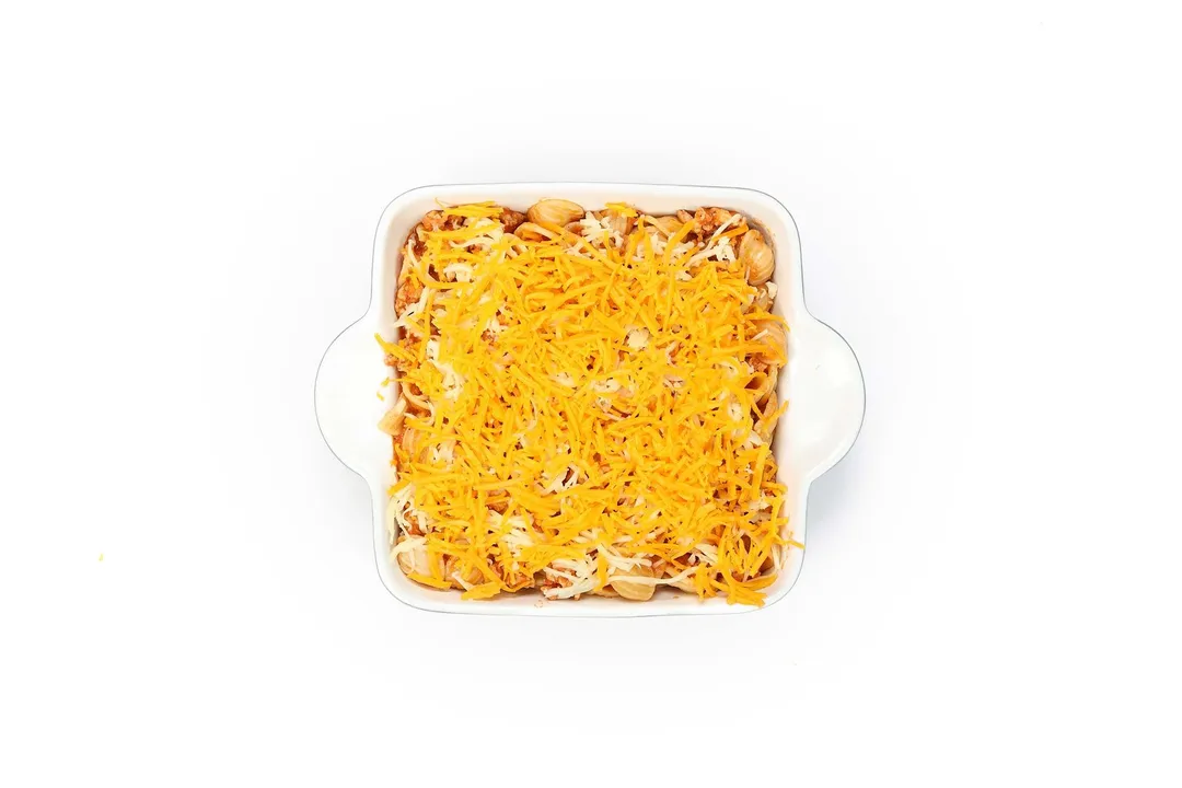 a casserole of cooked chicken pasta with shredded cheese on top