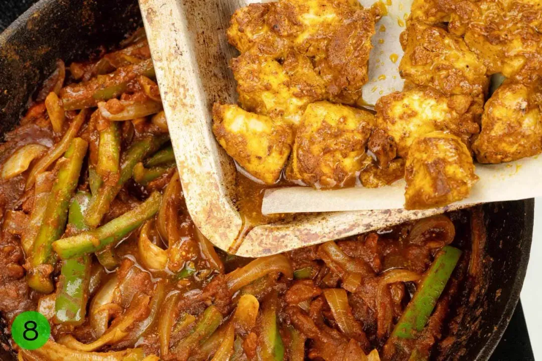 A sheetpan pouring chicken covered in sauce into a pan with vegetables covered in a dark brown sauce