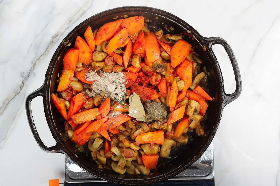 chopped carrots and seasoning cooking in a cast iron skillet