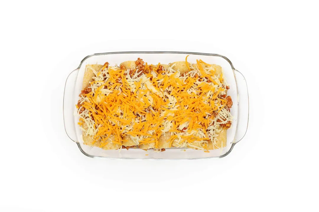 shredded cheese on top of a casserole of tortillas