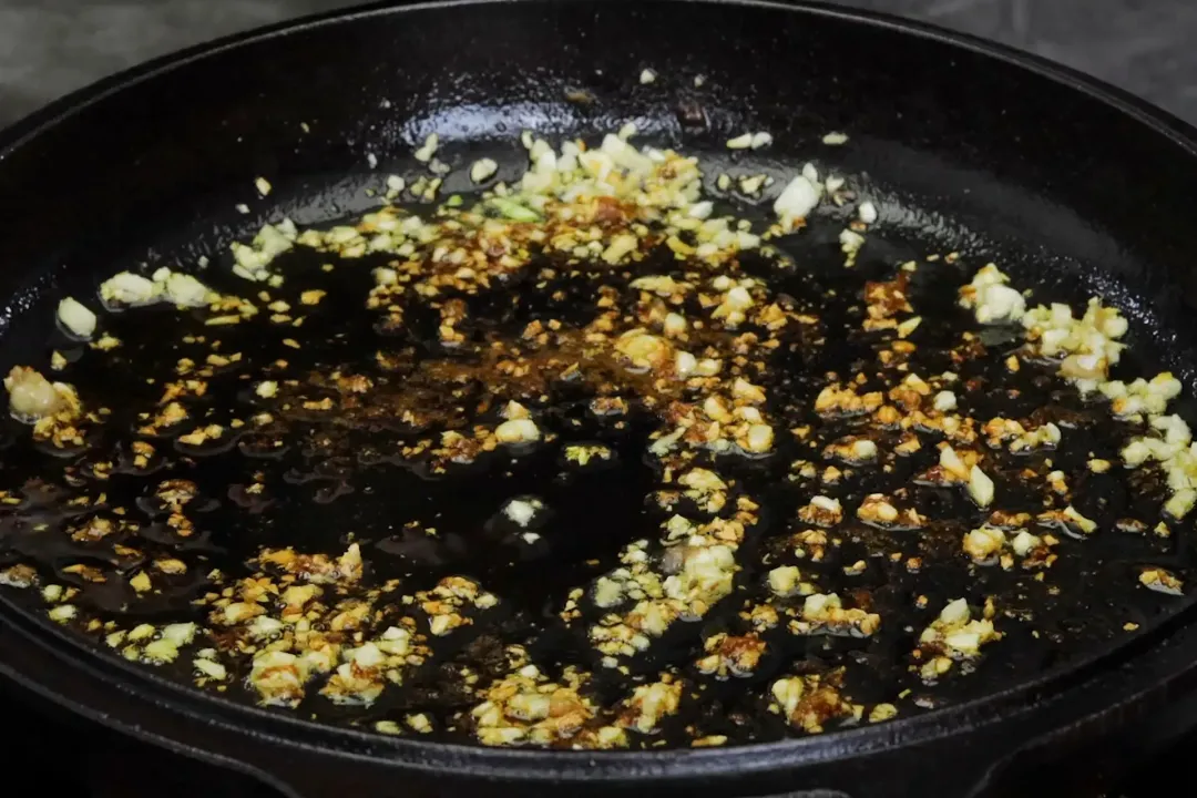 A skillet's bottom scattered with minced garlic and diced onion.