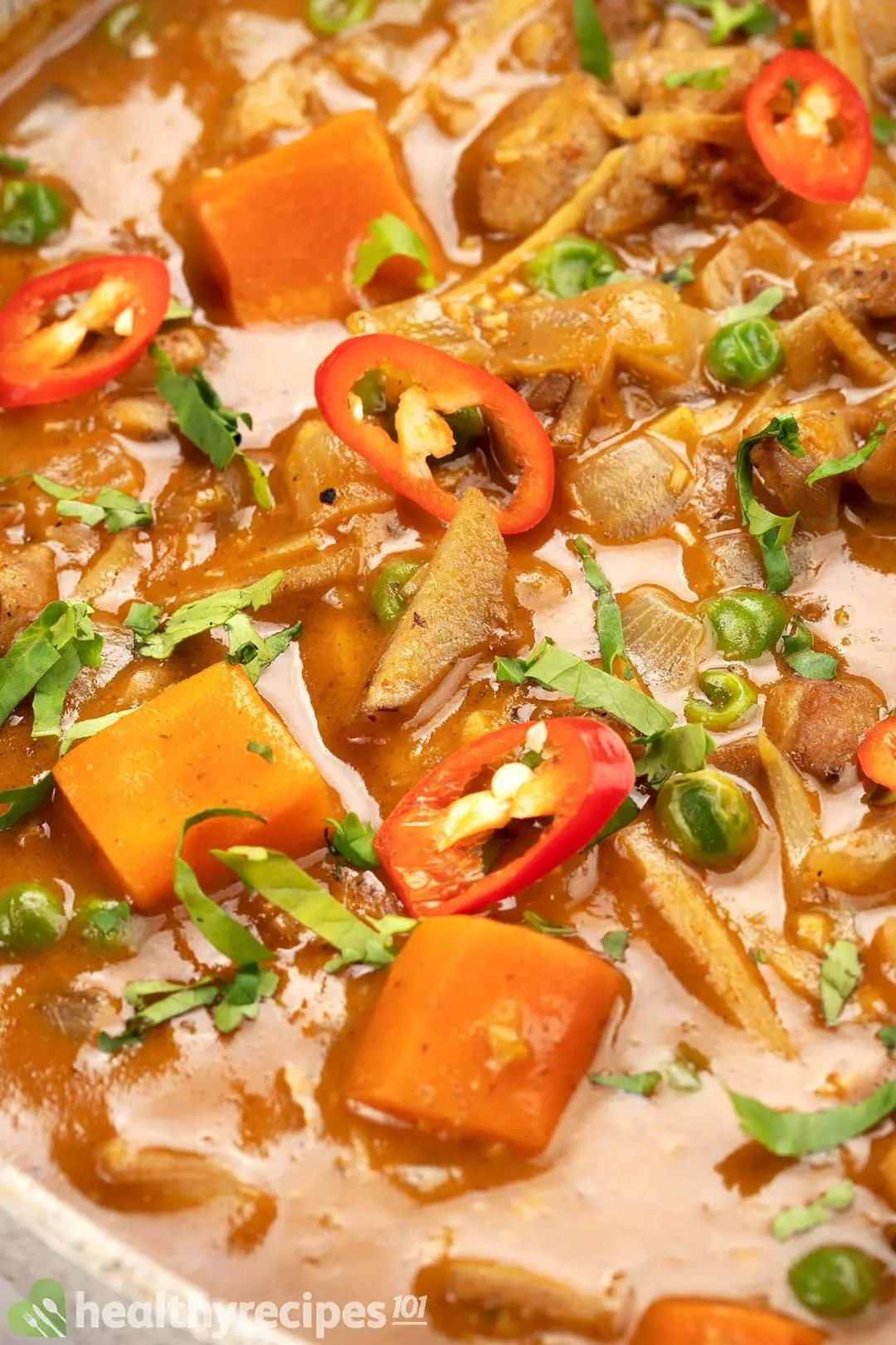 close-up shot of thai chicken curry with cubed carrot, sliced chile pepper, chopped coriander