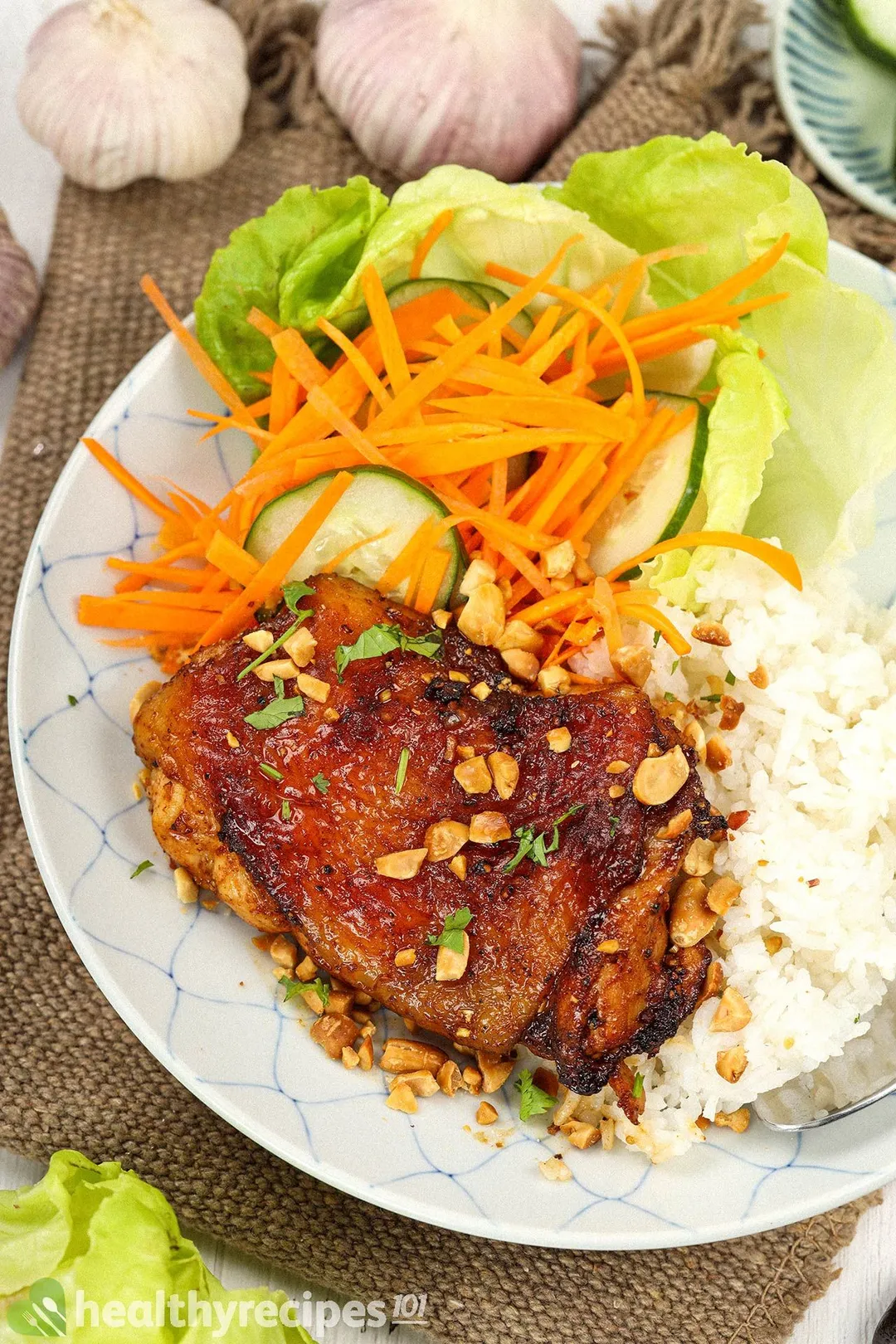 A piece of Thai chicken served with pickled vegetables, lettuce, peanuts, and white rice