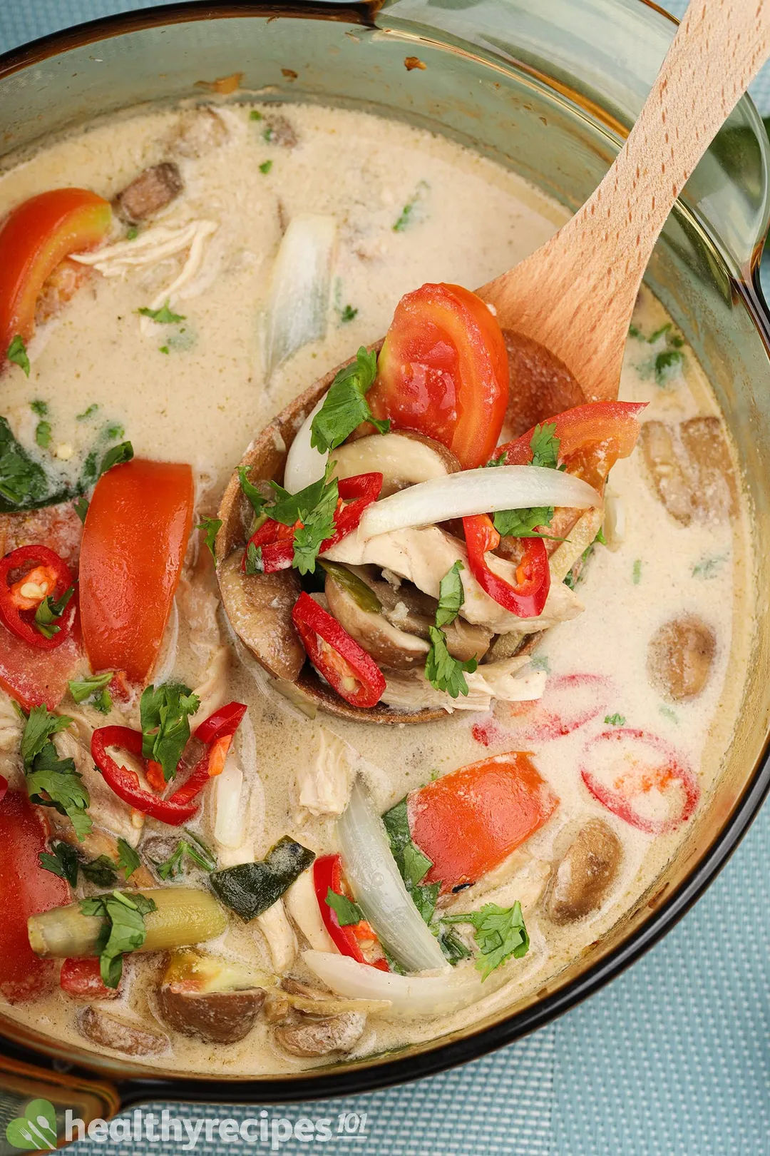 a wooden spoon in a pot of tom kha soup