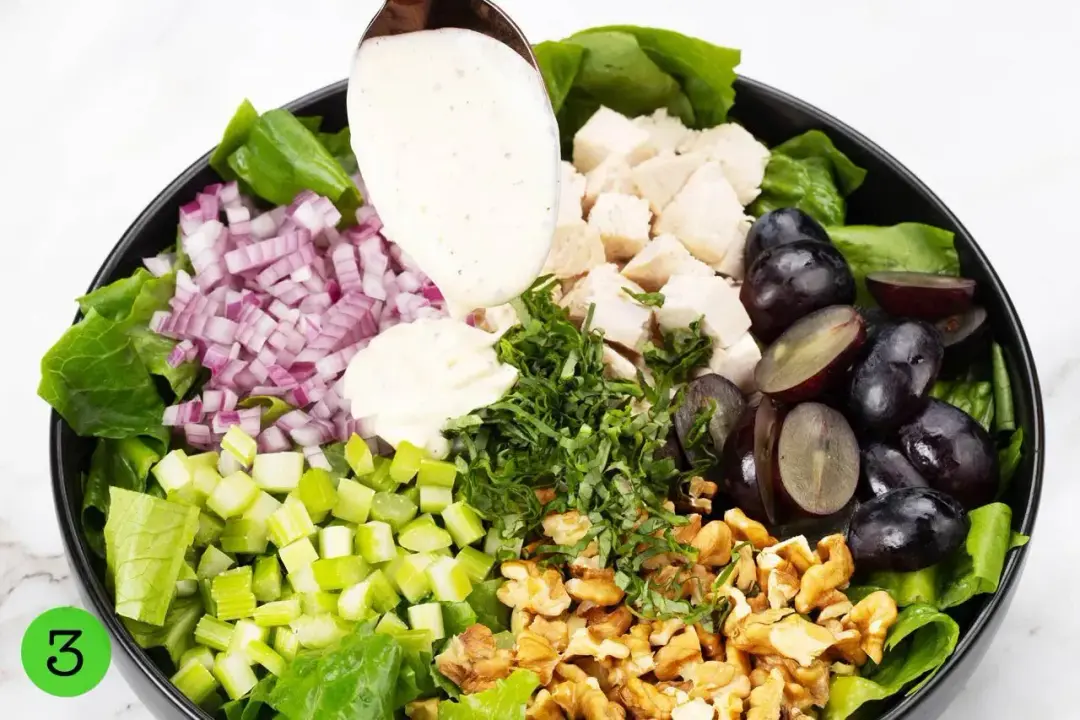 Vibrant ingredients with veggies, fruits, and nuts on a plate, dolloped with a mayonnaise dressing