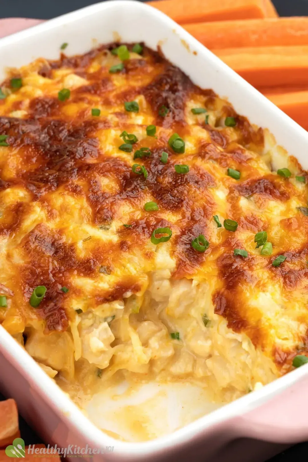 A ceramic sheet pan filled with Buffalo Chicken Dip that's been sliced off at the corner