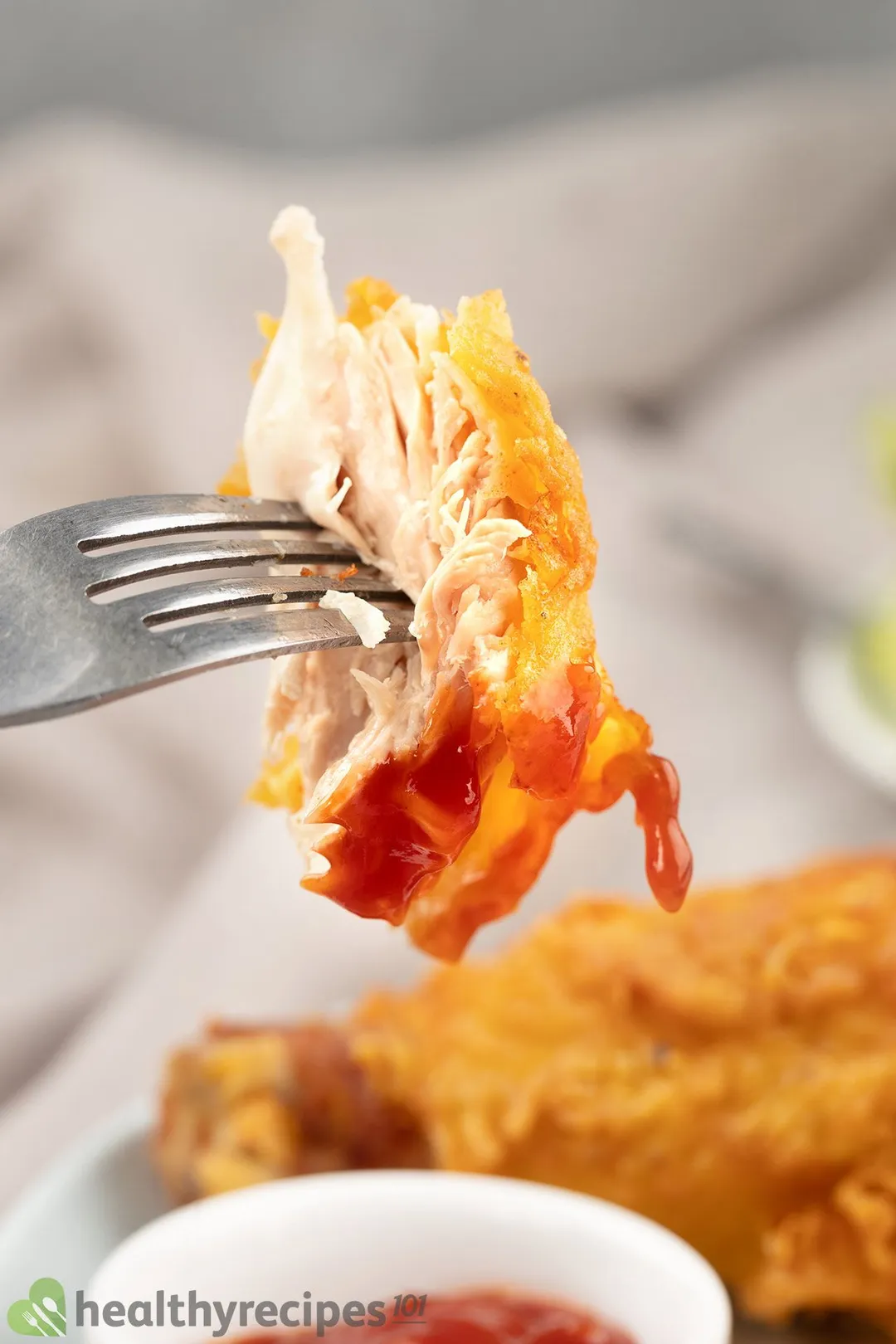 fork hold a piece of cooked chicken on top of a plate of chicken drumsticks